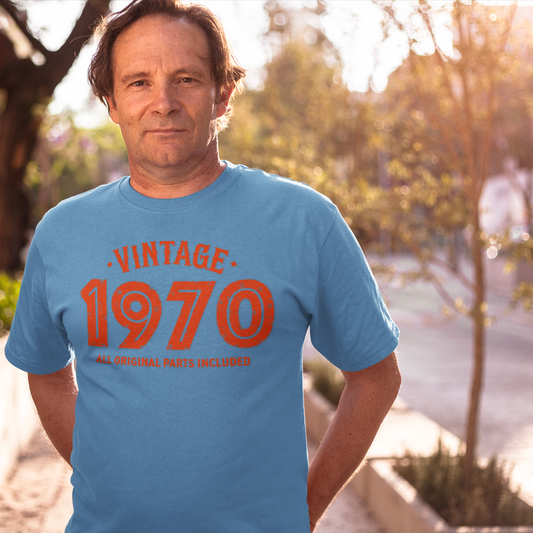 Man wearing a blue t-shirt with 'Vintage 1970' text outdoors.