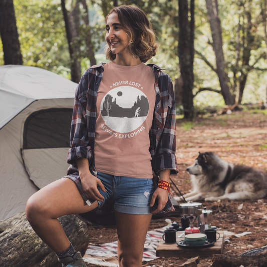 Woman sitting on a log in a forest with a tent and dog in the background