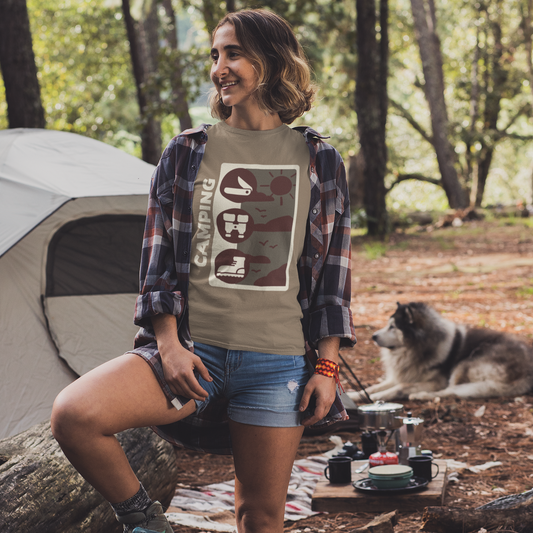 Woman sitting outdoors near a tent with a dog, wearing a graphic t-shirt and plaid shirt.
