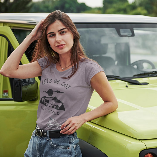 Woman standing next to a green vehicle wearing a t-shirt with text and graphics.