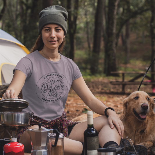 Woman camping with a dog, cooking outdoors in a forest setting