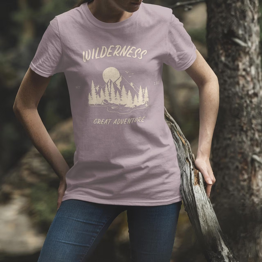 Person wearing a t-shirt with 'Wilderness Great Adventure' design in a forest setting