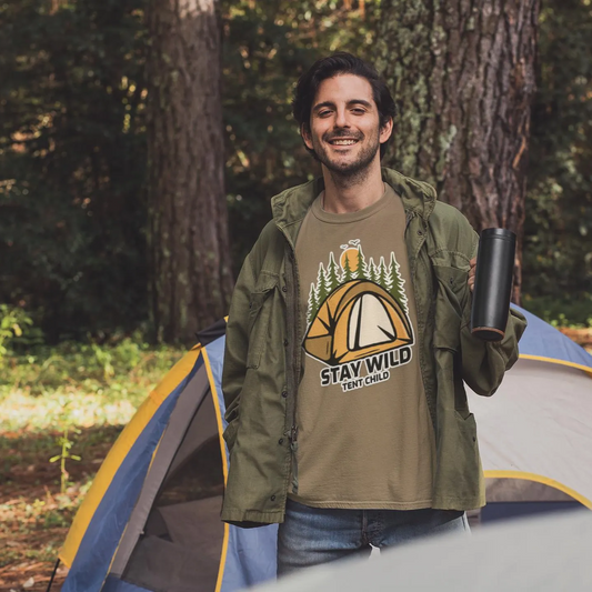 Man standing in front of a tent wearing a 'Stay Wild, Keep It Wild' t-shirt in a forest setting.