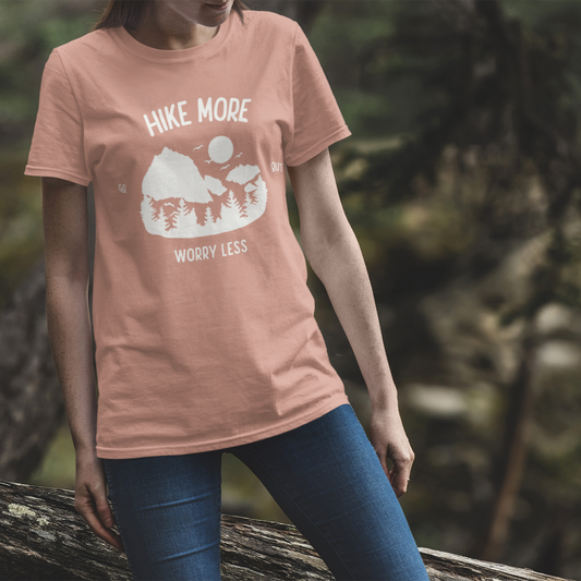 Person wearing a pink t-shirt with 'Hike More Worry Less' design in a forest setting