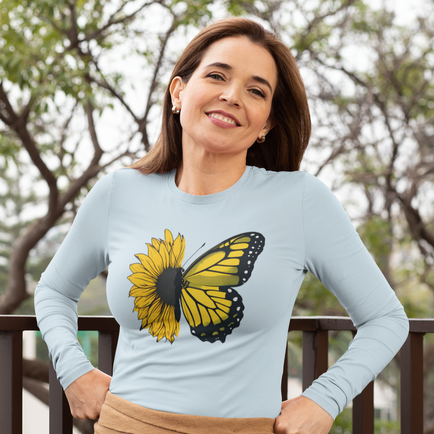 Woman wearing a light blue sweater with a butterfly design outdoors.