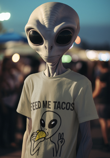 Person wearing an alien head costume with a 'Feed Me Tacos' t-shirt featuring an alien eating a taco.