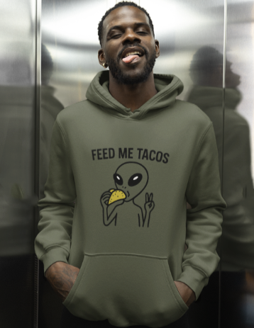 Person wearing a green hoodie with an alien eating a taco graphic and 'Feed Me Tacos' text.