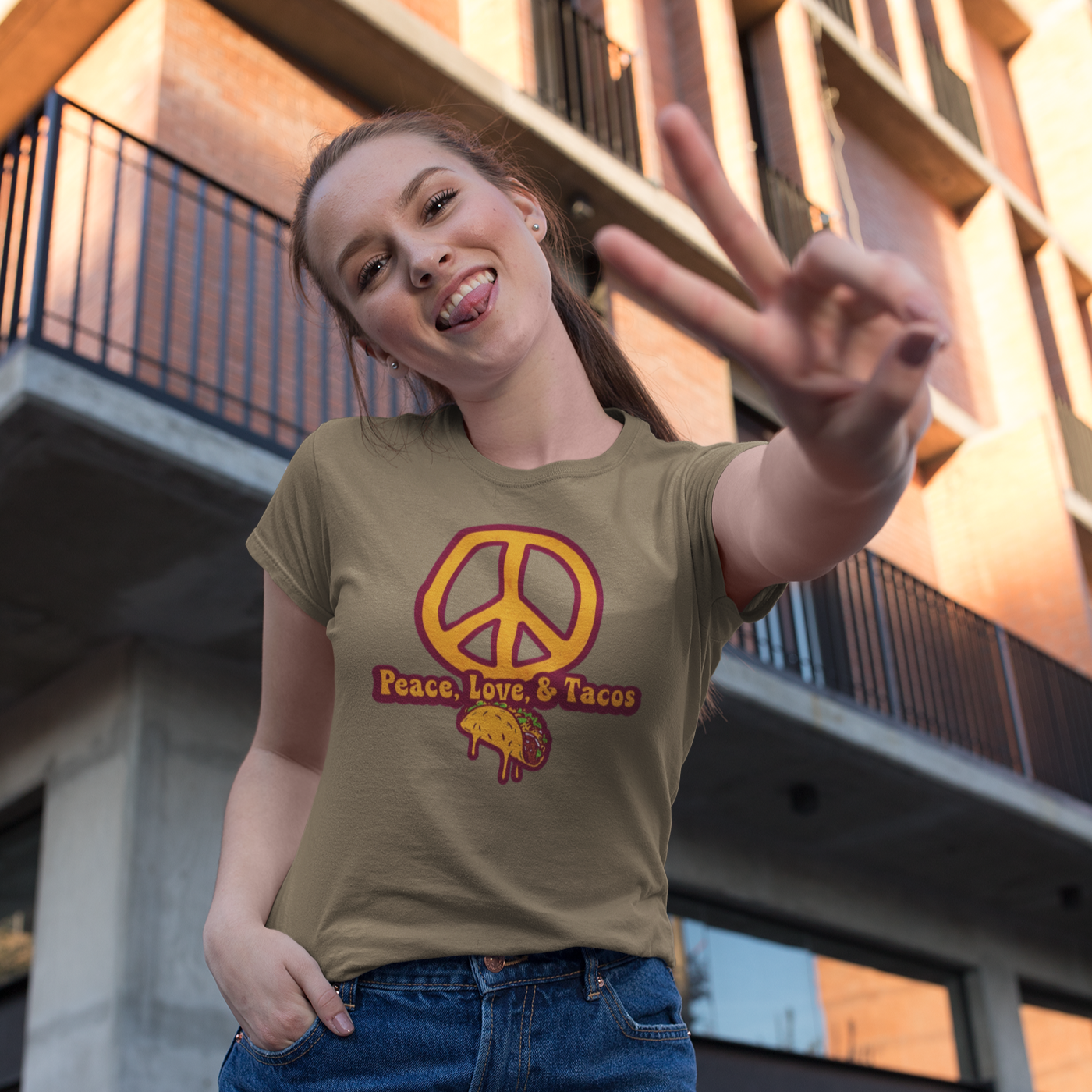 Person wearing a t-shirt with a peace symbol and 'Peace Love & Tacos' text, standing in front of a building.
