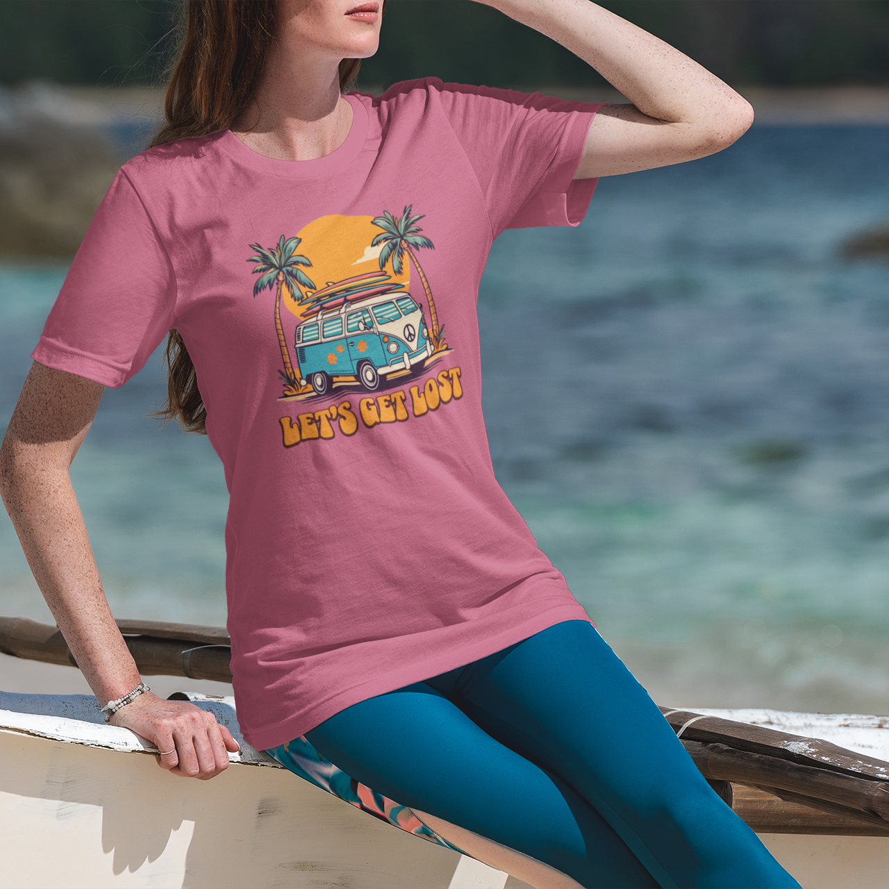 Person wearing a pink t-shirt with a graphic design by the sea