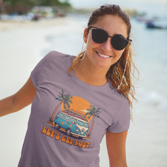 Woman wearing sunglasses and a t-shirt with a graphic design on a beach.