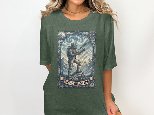 Green t-shirt with a graphic of a diver playing a harp in mountains, "Weird Girls Club" banner.