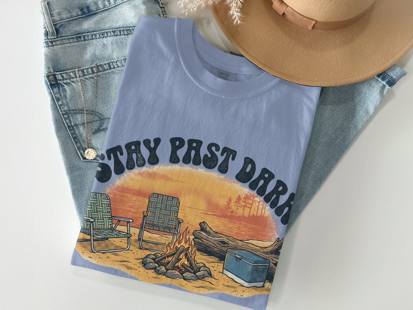 Light blue t-shirt with "STAY PAST DARK" text over a campfire scene.