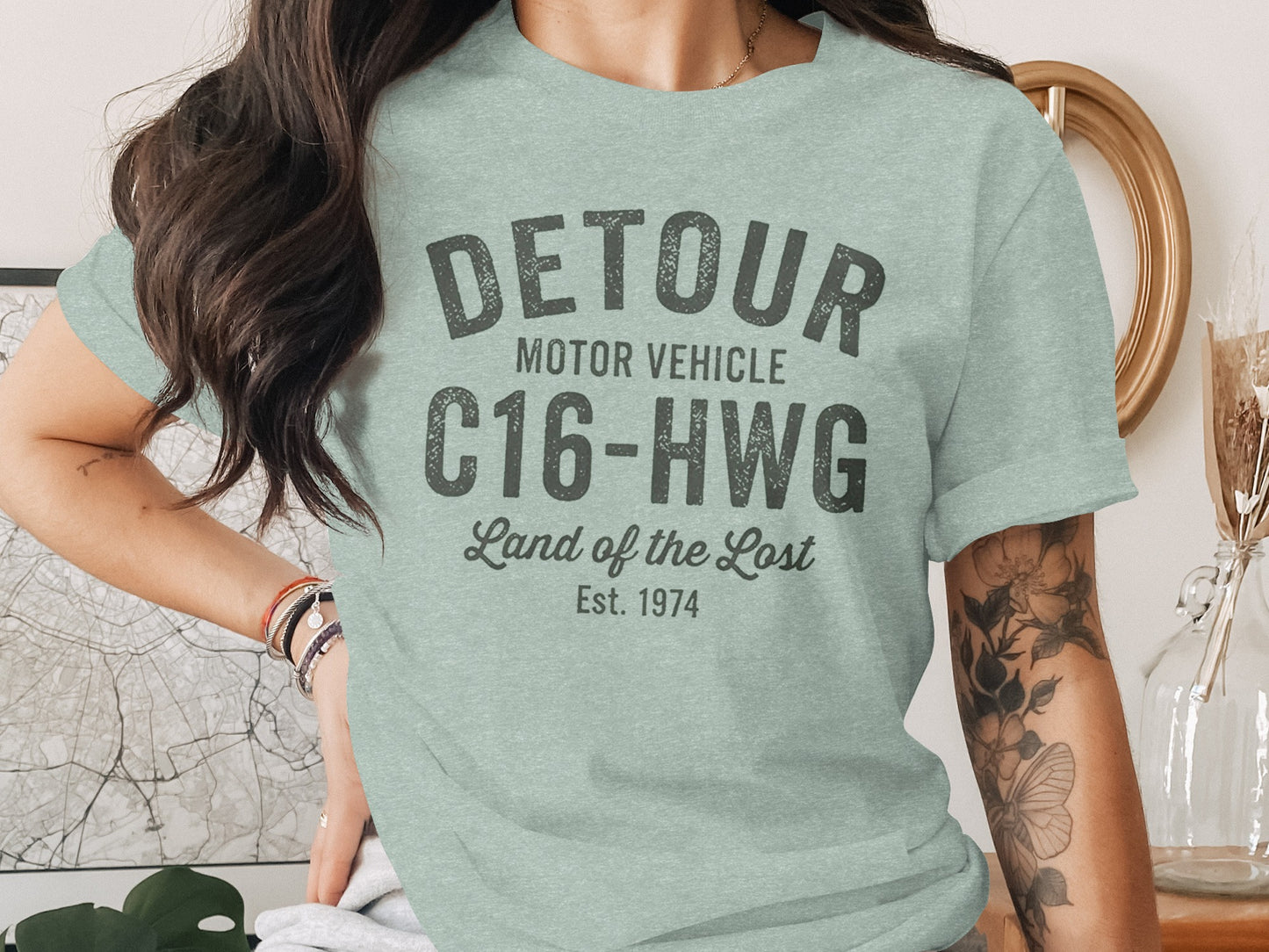 Light green t-shirt with "DETOUR MOTOR VEHICLE C16-HWG Land of the Lost Est. 1974" text.