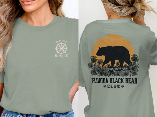 Green t-shirt with a compass graphic and text on the front, and a bear in a landscape on the back.