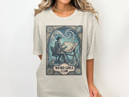 T-shirt graphic of a woman at a drafting table with cats, "Weird Girls Club" text.