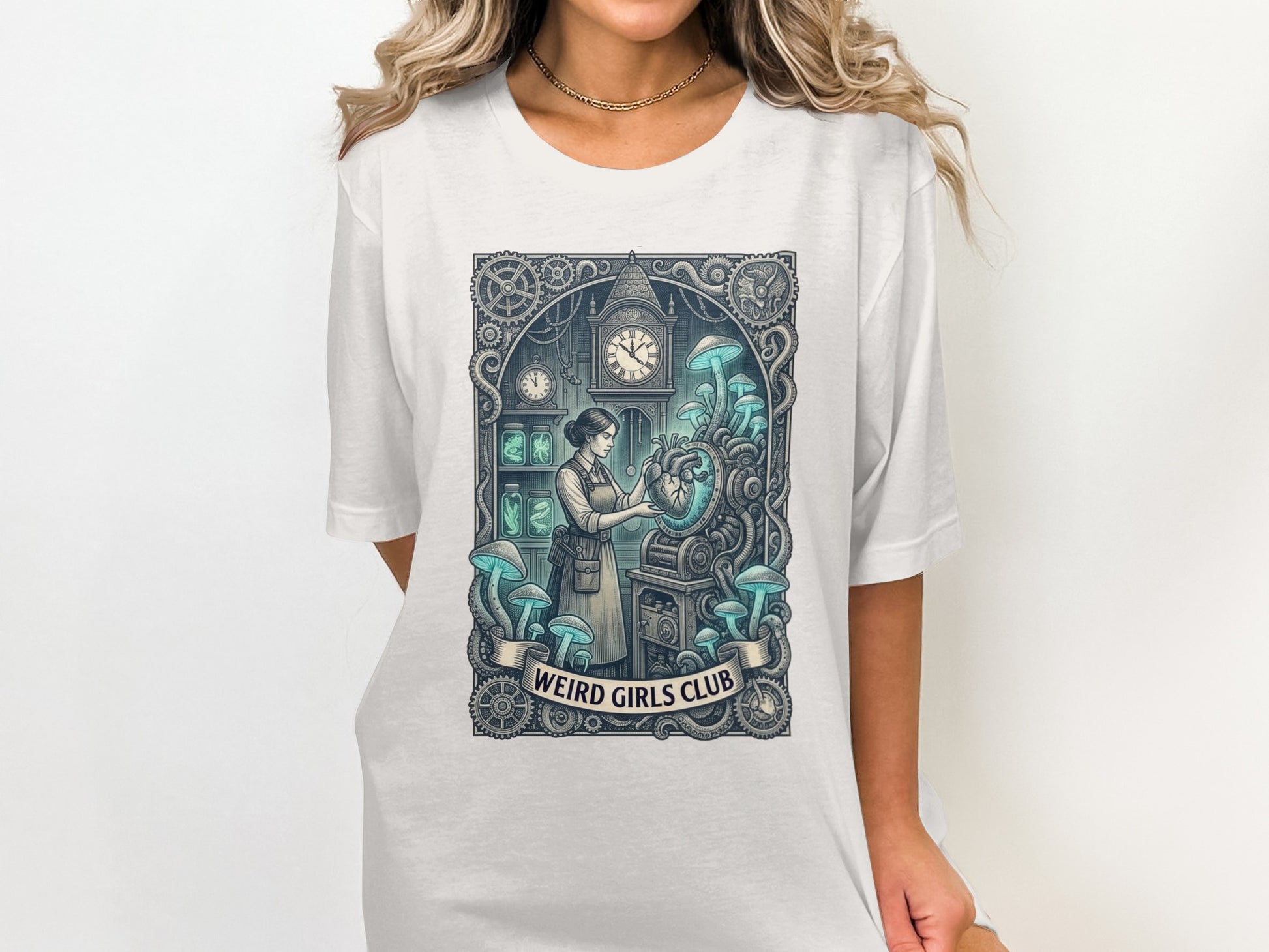 White t-shirt featuring a clockwork heart and mushrooms illustration with "Weird Girls Club" text.