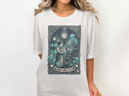 White t-shirt featuring a clockwork heart and mushrooms illustration with "Weird Girls Club" text.