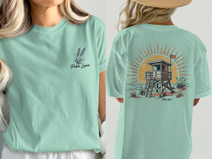 Front: Puka Luna text and grass. Back: Beach lifeguard tower and sun.