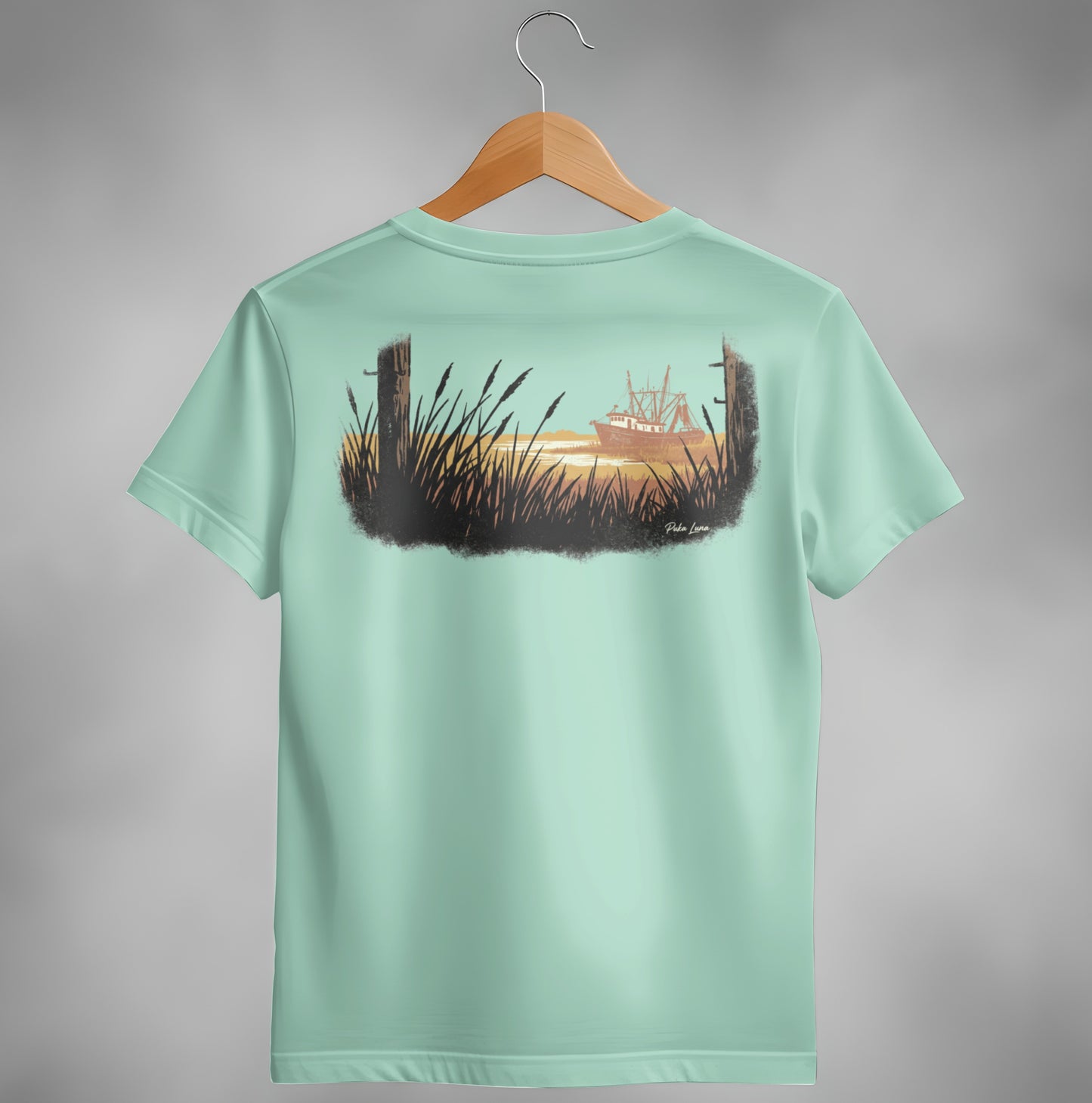Mint green t-shirt with serene coastal artwork featuring a ship at sunset.