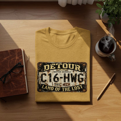 Detour 'Land of the Lost' Vintage | Vintage Outdoor Apparel: Yellow t-shirt with "Detour Motor Vehicle C16-HWG Land of the Lost" license plate graphic.