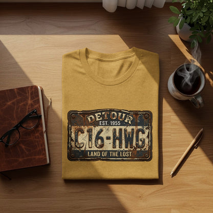 Land of the Lost Detour Plate: The Explorer's Adventure Tee: Yellow t-shirt with "Detour C16-HWG Land of the Lost Est. 1955" license plate graphic.