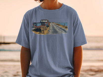 Blue t-shirt with graphic of vintage truck and "FRESH CRAB" sign on beach road.