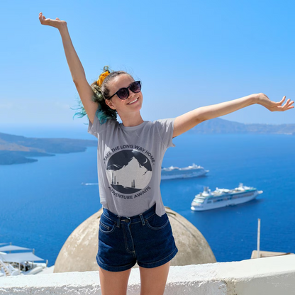 Woman with arms outstretched in front of a scenic view with boats and blue sky.