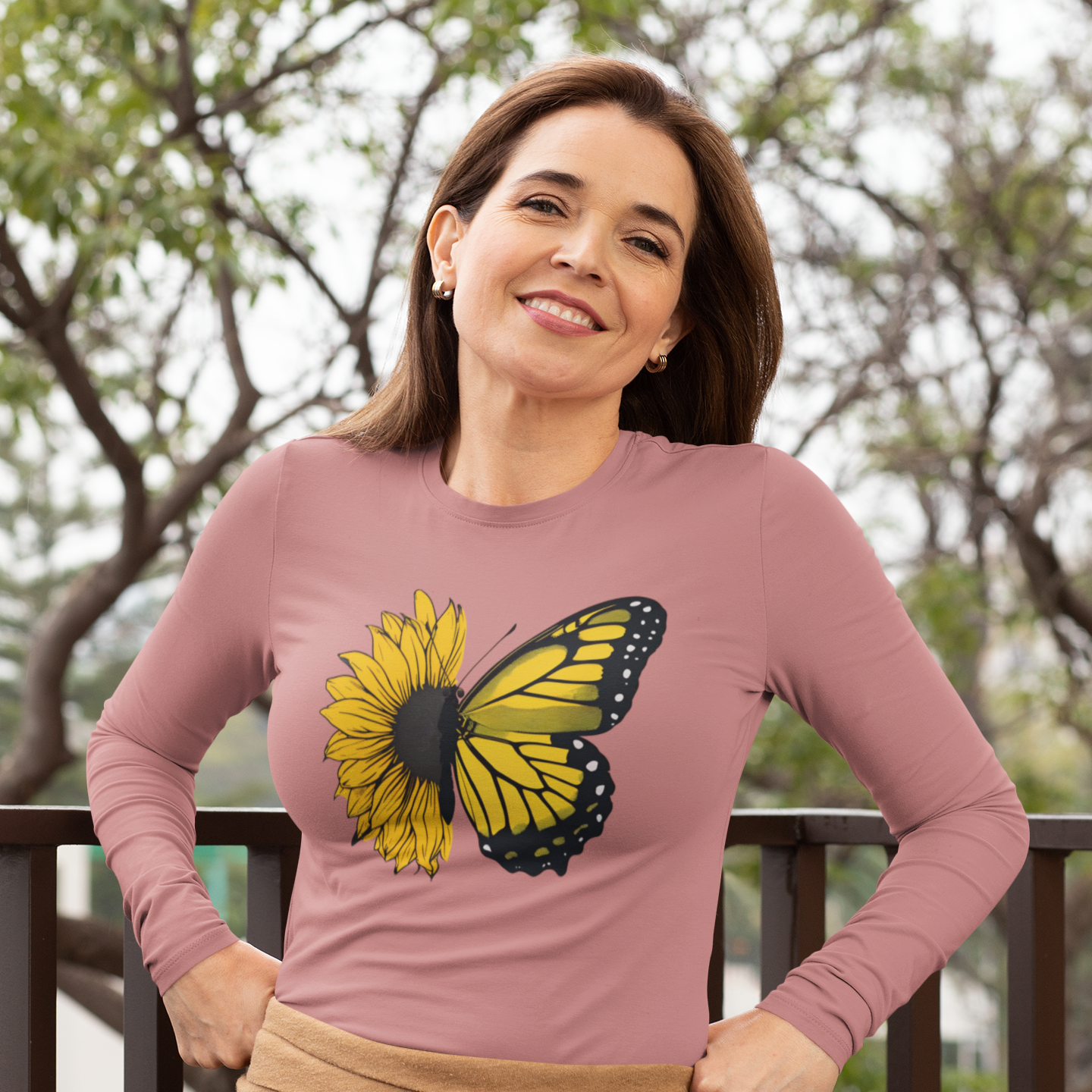 Woman wearing a pink long-sleeve shirt with a butterfly design outdoors.