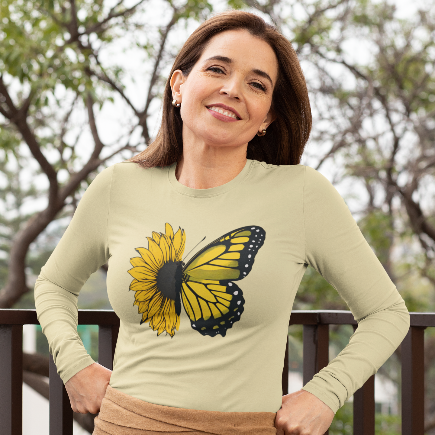 Woman wearing a light green long-sleeve shirt with a butterfly design outdoors.