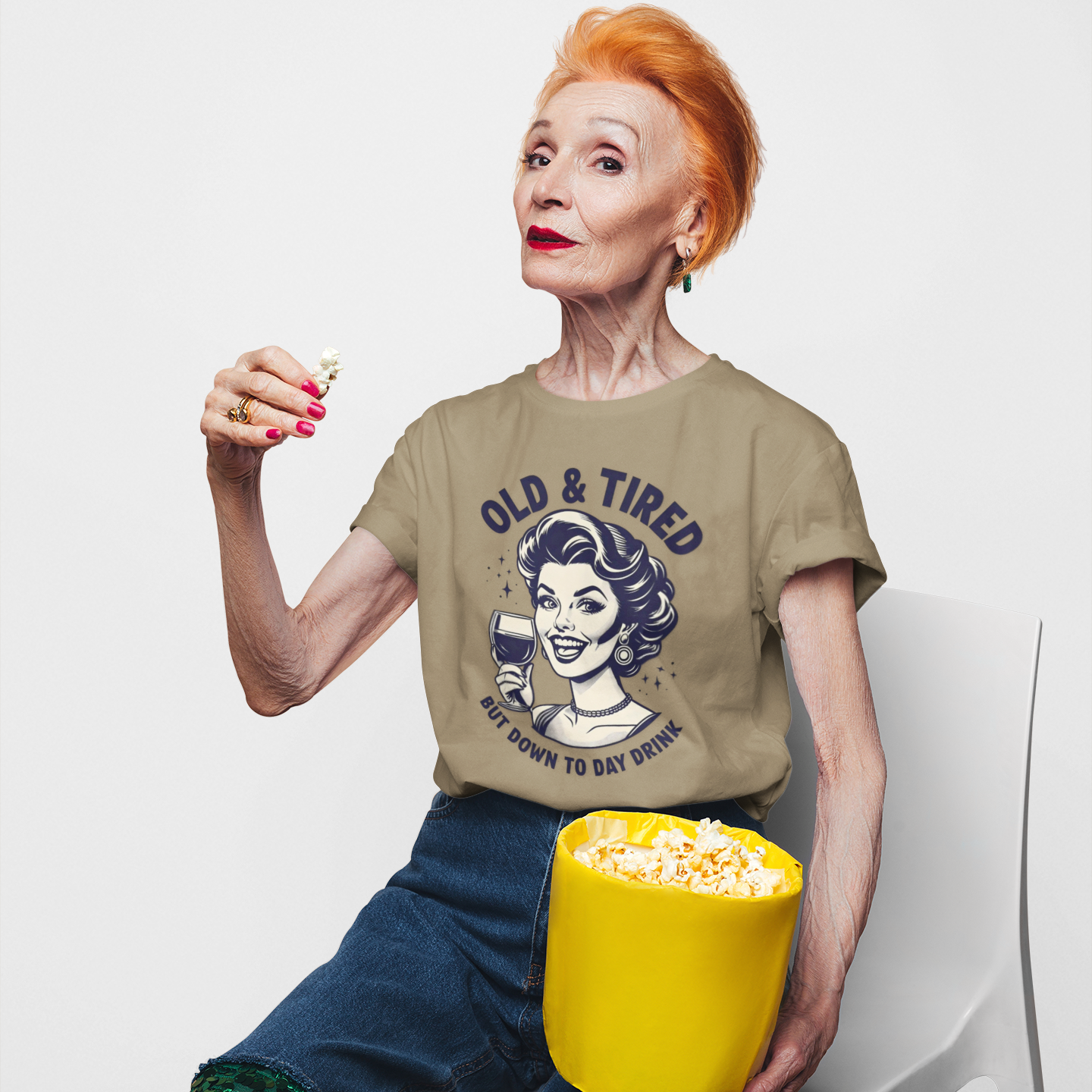 Person wearing a t-shirt with a graphic design, sitting with a bucket of popcorn on a white background