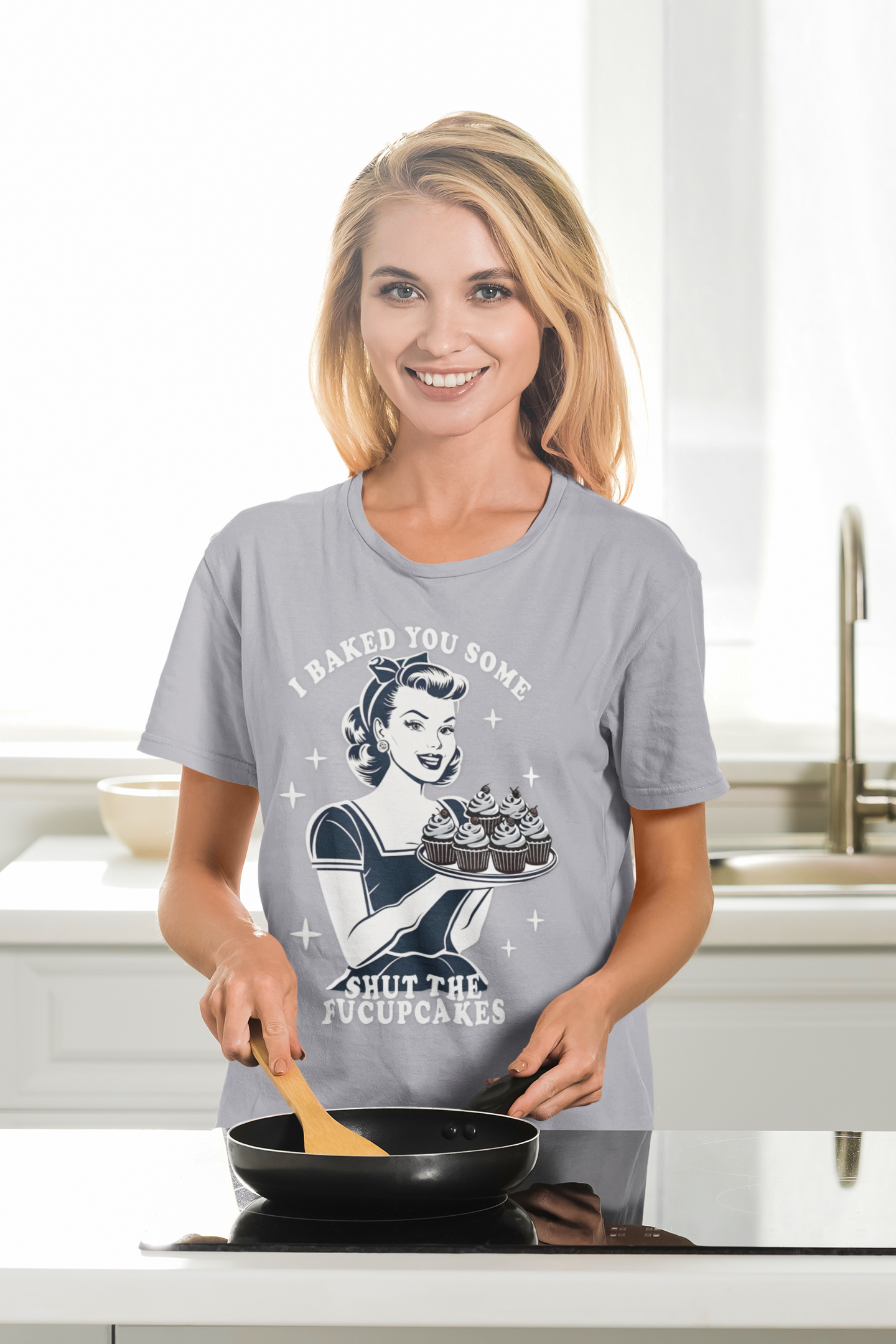 Woman wearing a graphic t-shirt in a kitchen holding a pan.