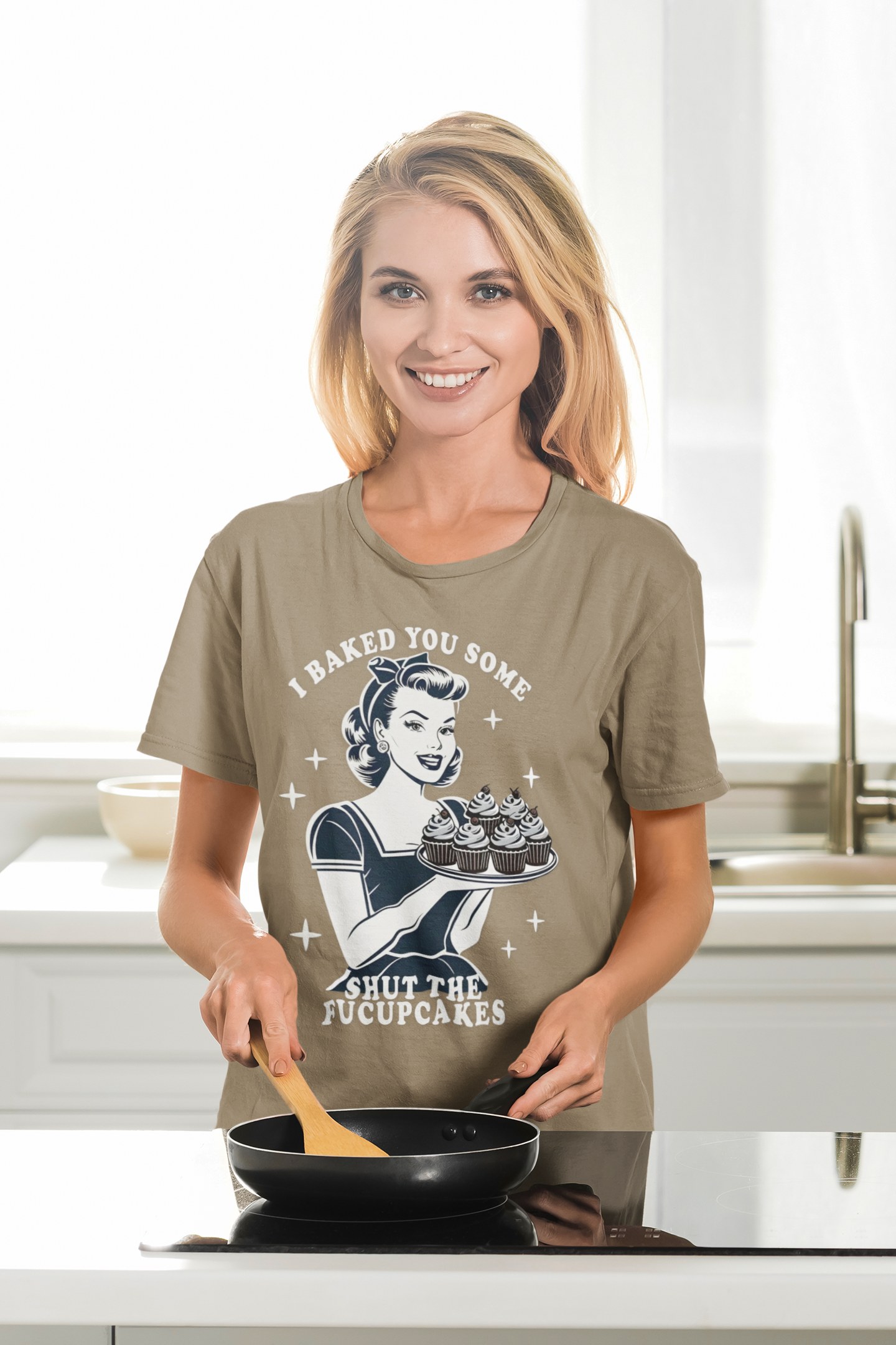 Woman wearing a graphic t-shirt in a kitchen holding a pan.