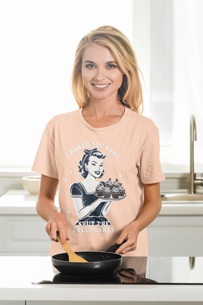 Woman wearing a graphic t-shirt in a kitchen holding a pan.