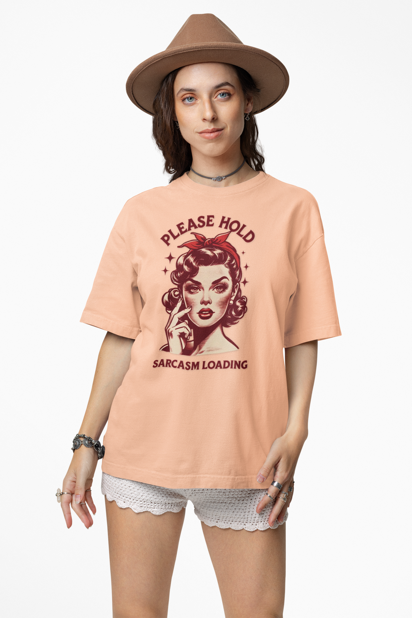 Woman wearing a peach t-shirt with a graphic design and text, standing against a white background.