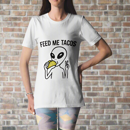 Person wearing a white t-shirt with an alien eating a taco graphic and 'Feed Me Tacos' text.