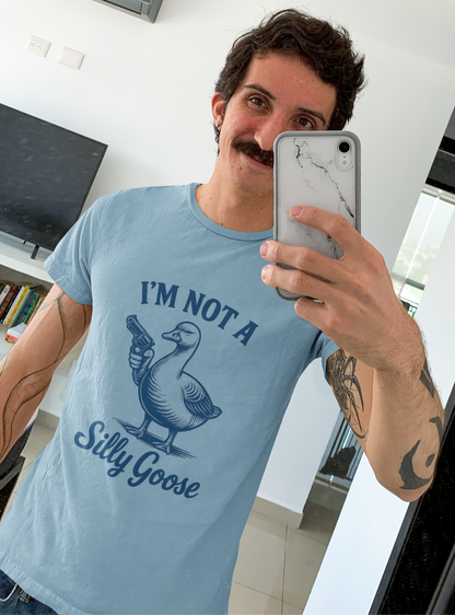 Man taking a mirror selfie wearing a light blue t-shirt with a goose graphic and text.