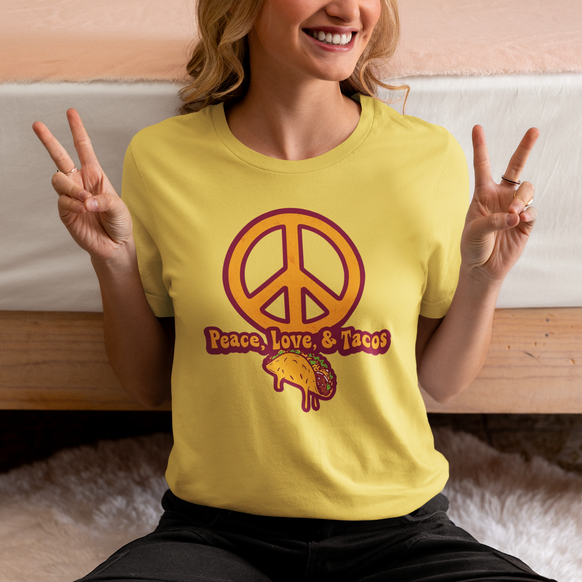 Person wearing a yellow t-shirt with a peace symbol and 'Peace, Love, & Tacos' text.