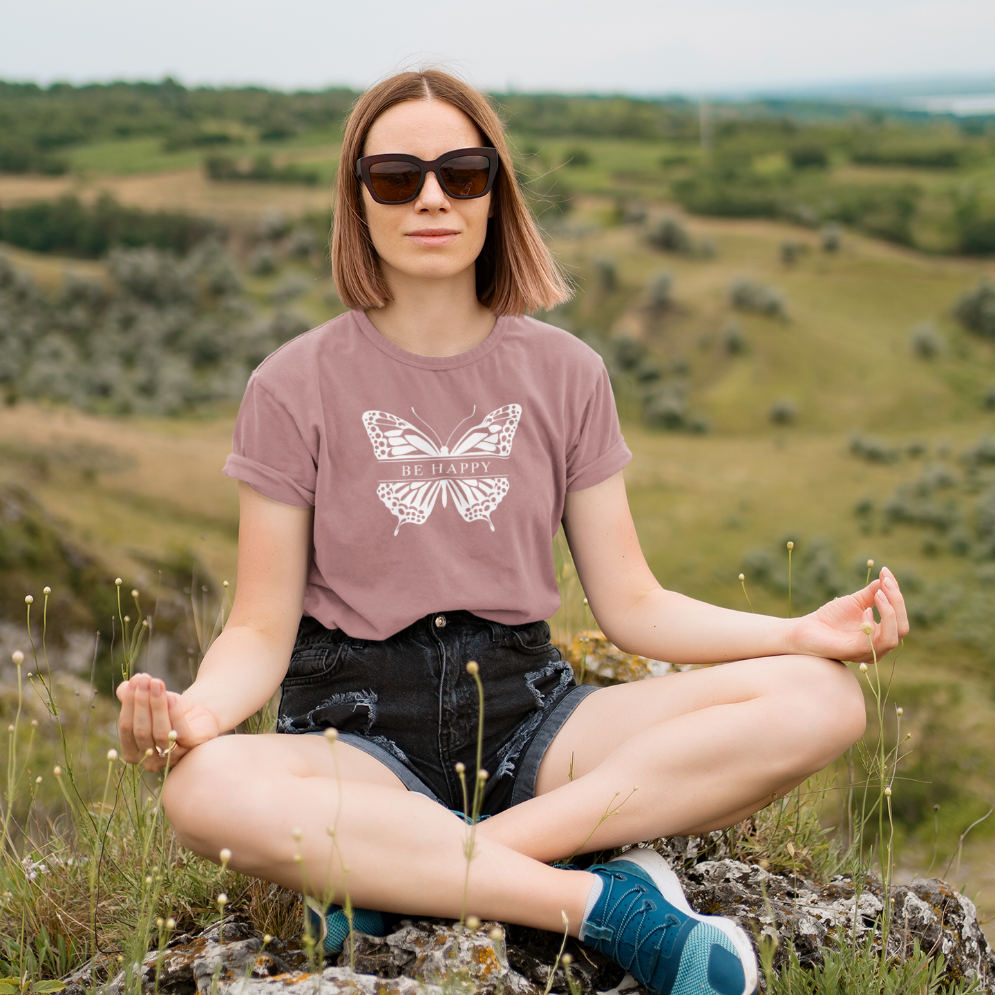 Woman sitting outdoors on a rock with a scenic background