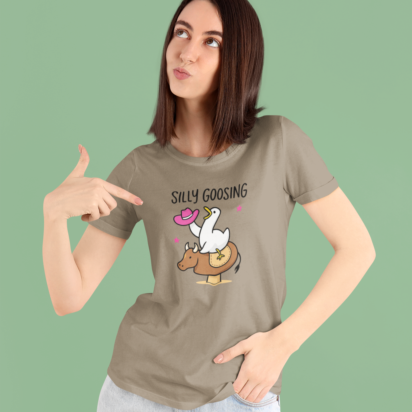 Woman wearing a t-shirt with a graphic of a goose and text 'Silly Goosing' on a green background