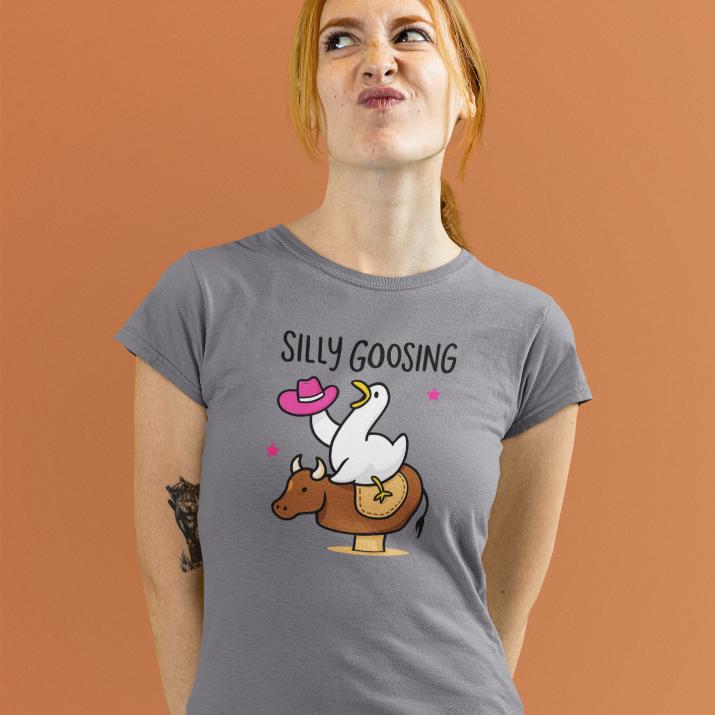 Person wearing a gray t-shirt with a graphic design and text on an orange background
