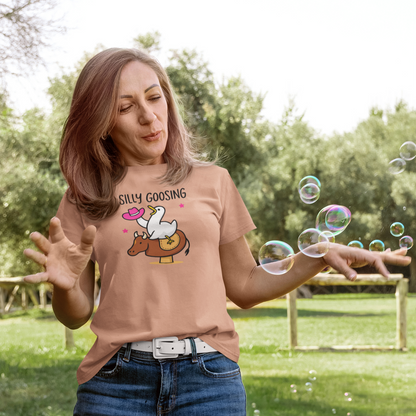 Woman blowing bubbles outdoors wearing a t-shirt with a graphic design.