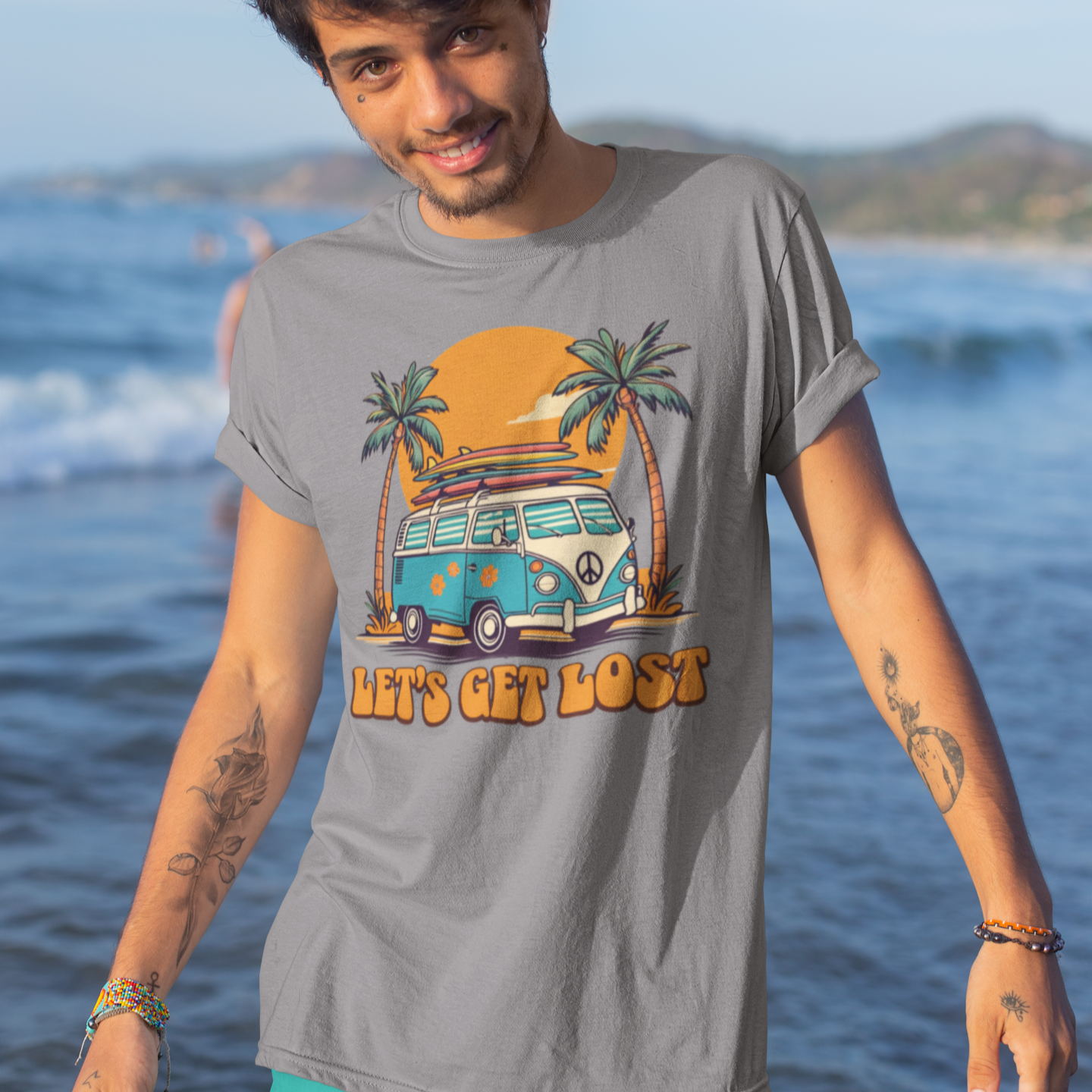 Man wearing a t-shirt with a graphic design of a van and palm trees on a beach.