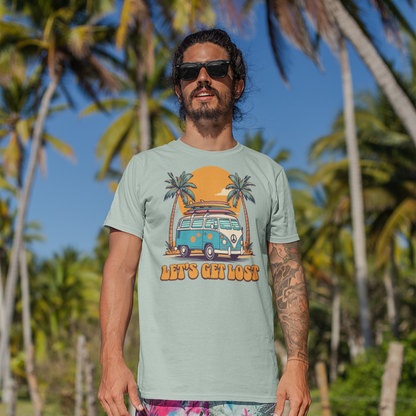 Man wearing a graphic t-shirt and colorful shorts standing on a beach with palm trees in the background
