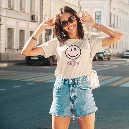 Woman wearing a t-shirt with a smiley face design and denim shorts on a city street.