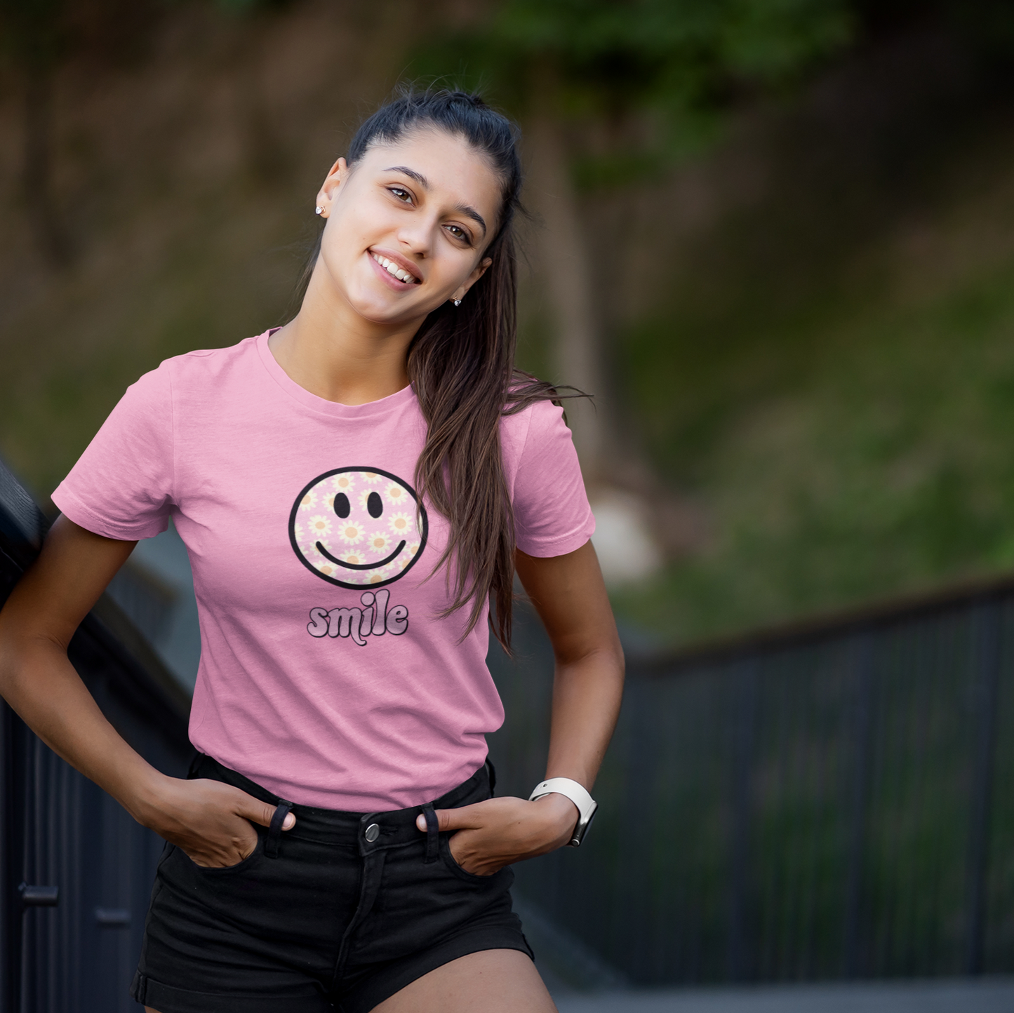 Woman wearing a pink t-shirt with a smiley face design outdoors
