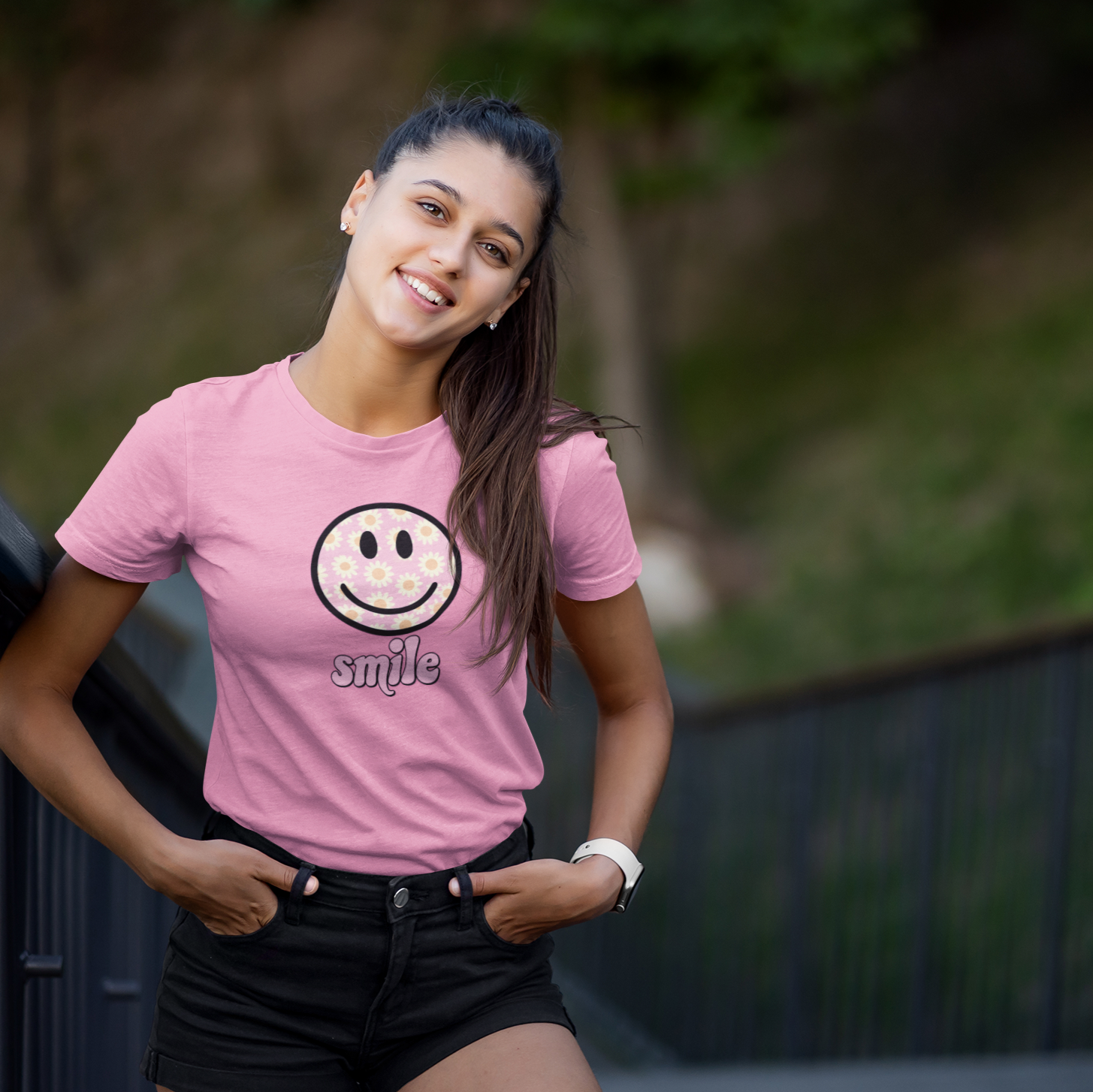 Woman wearing a pink t-shirt with a smiley face design outdoors