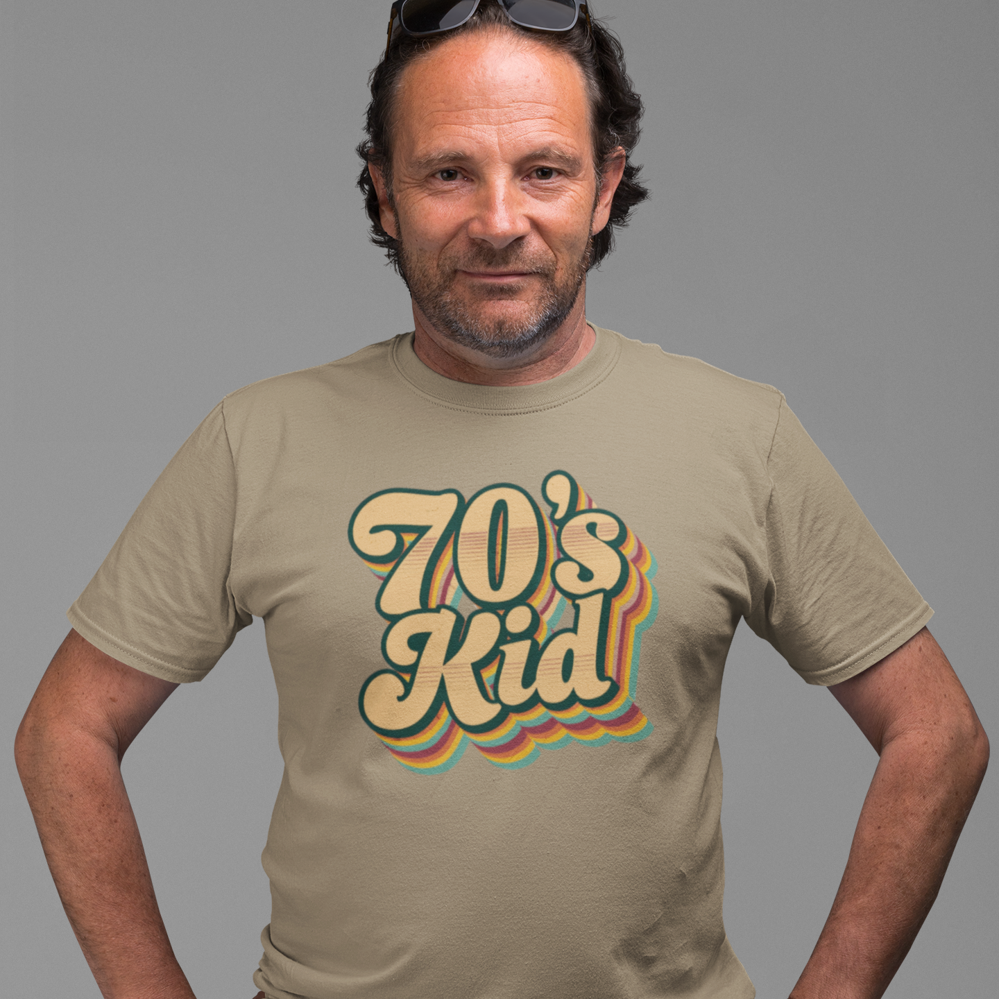 Man wearing a beige t-shirt with '70's Kid' design on a gray background