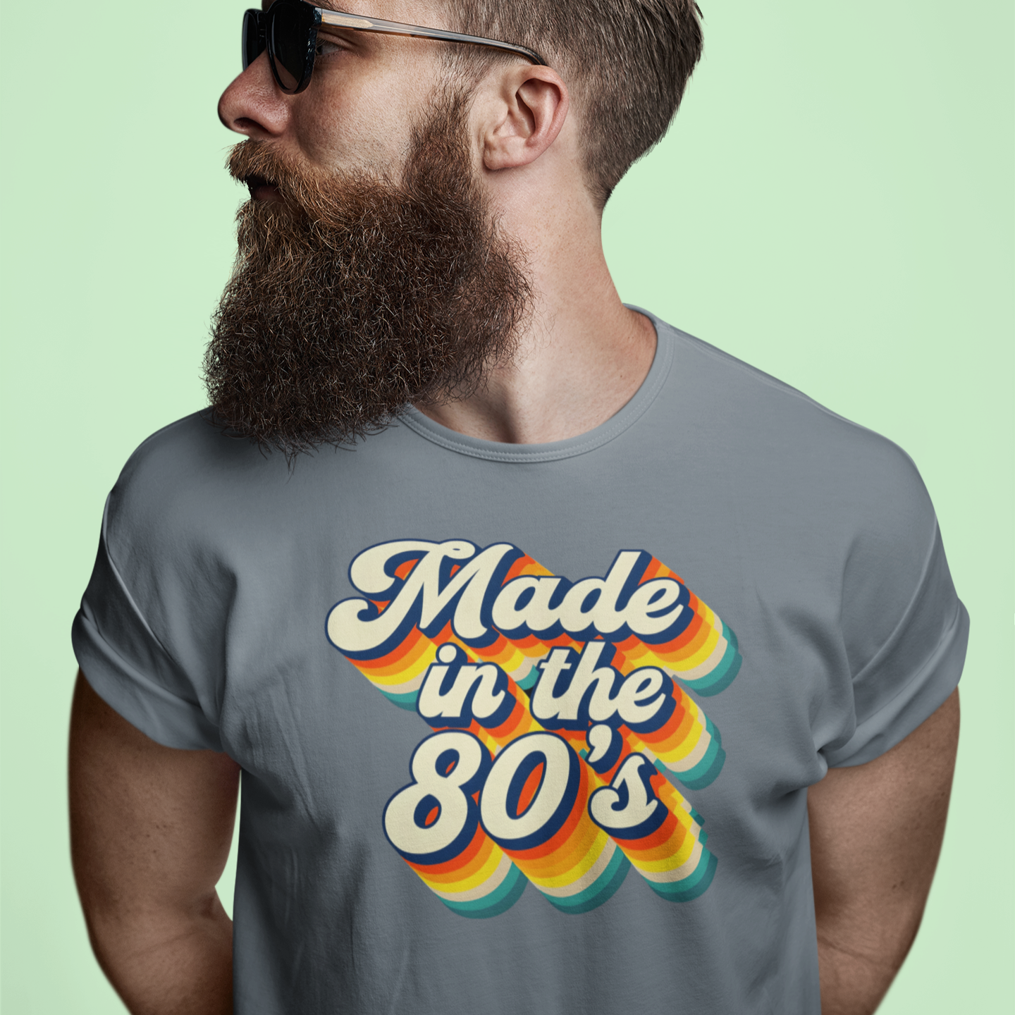 Man wearing sunglasses and a 'Made in the 80's' t-shirt against a light green background