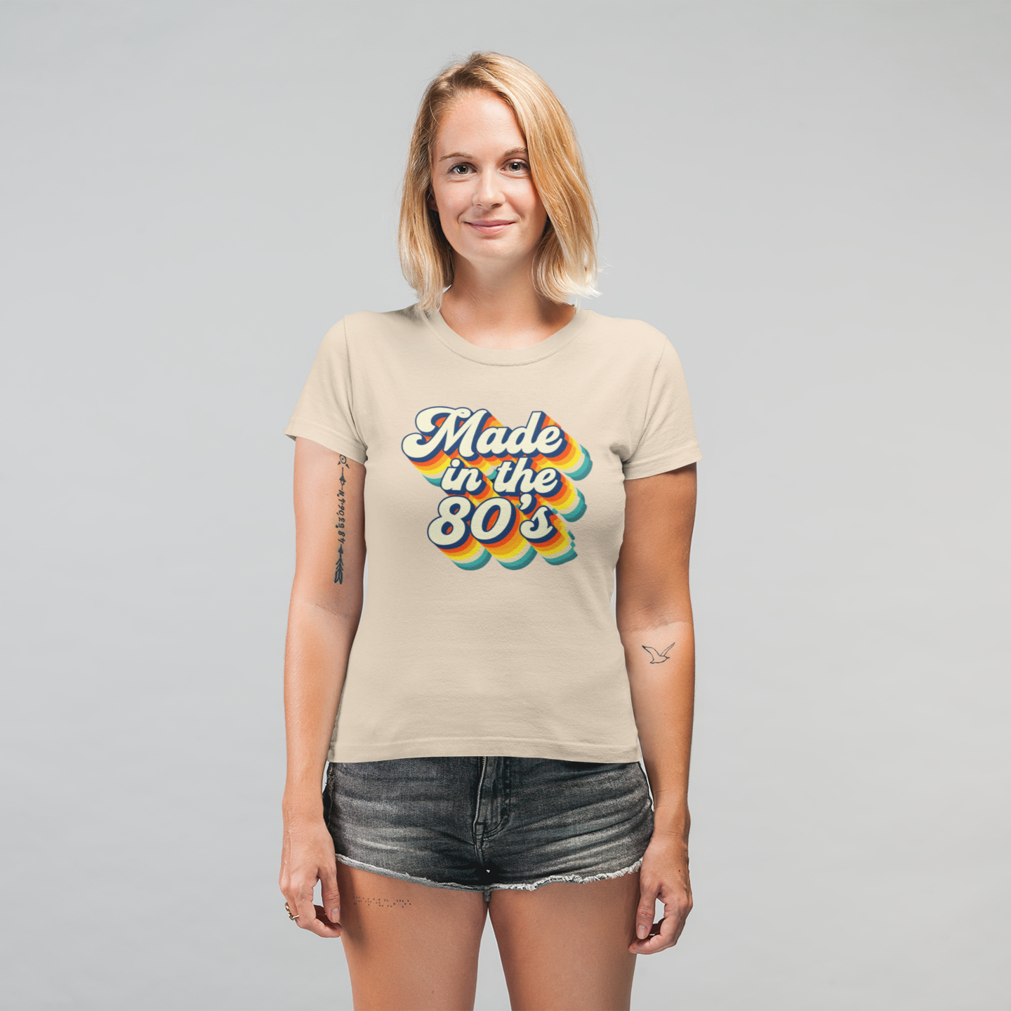 Woman wearing a beige t-shirt with 'Made in the 80s' design on a gray background