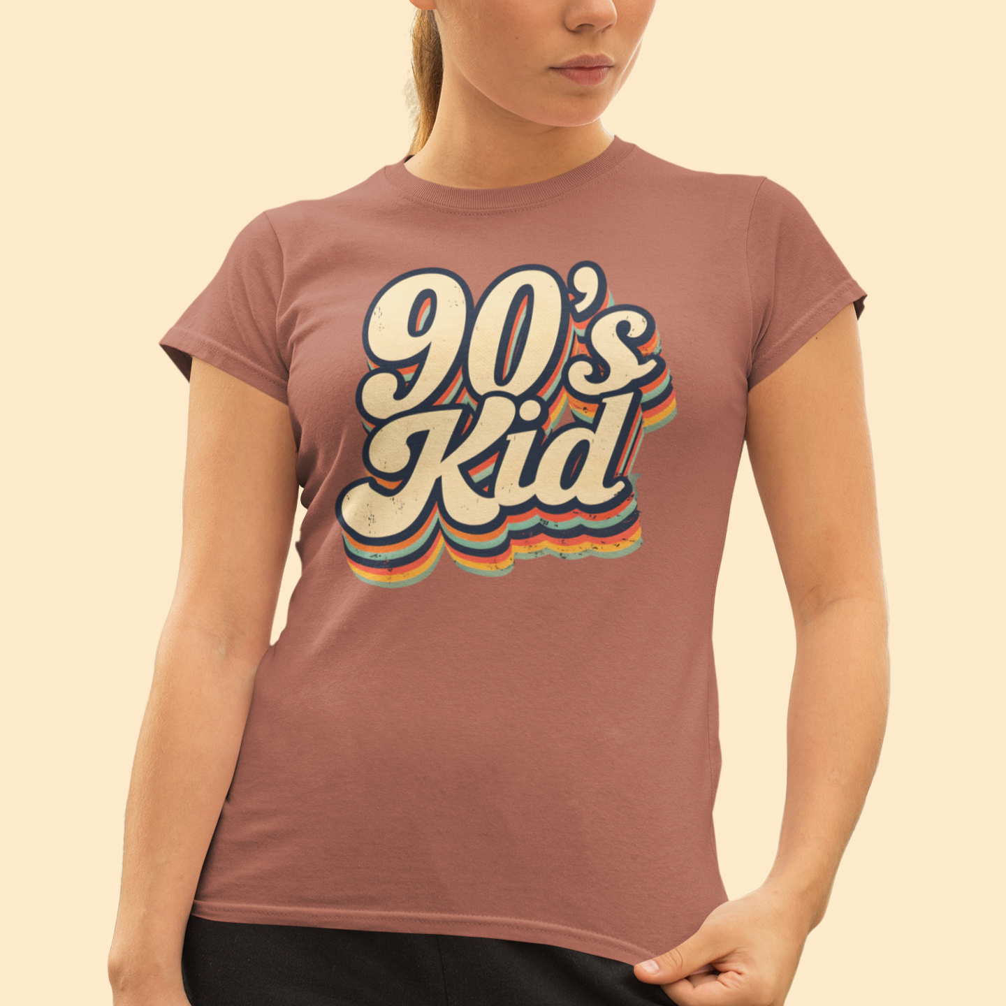 Woman wearing a '90's Kid' t-shirt against a beige background